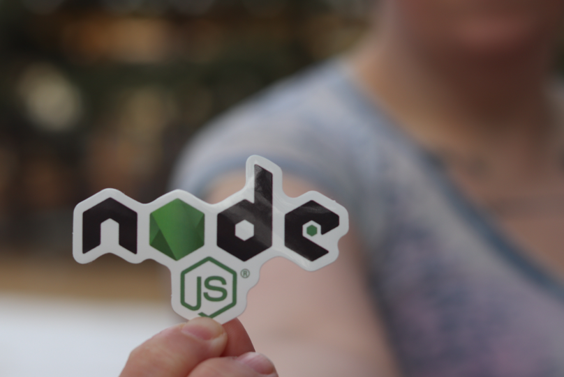 a person holding up a sticker with a node.js logo on it