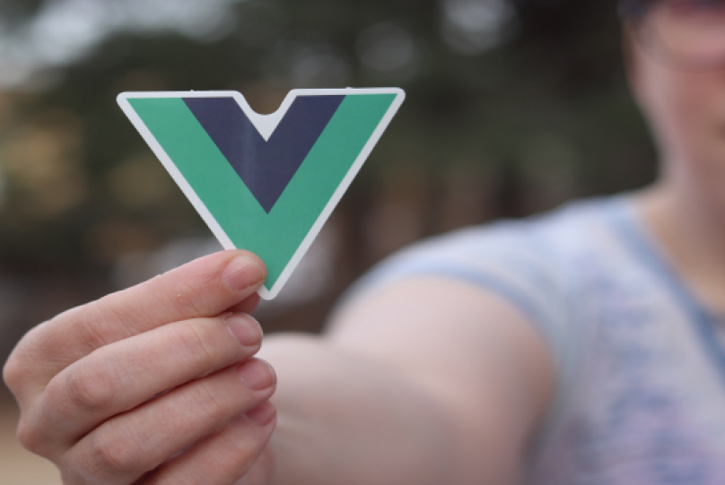 a person holding up a sticker with a vue.js logo on it